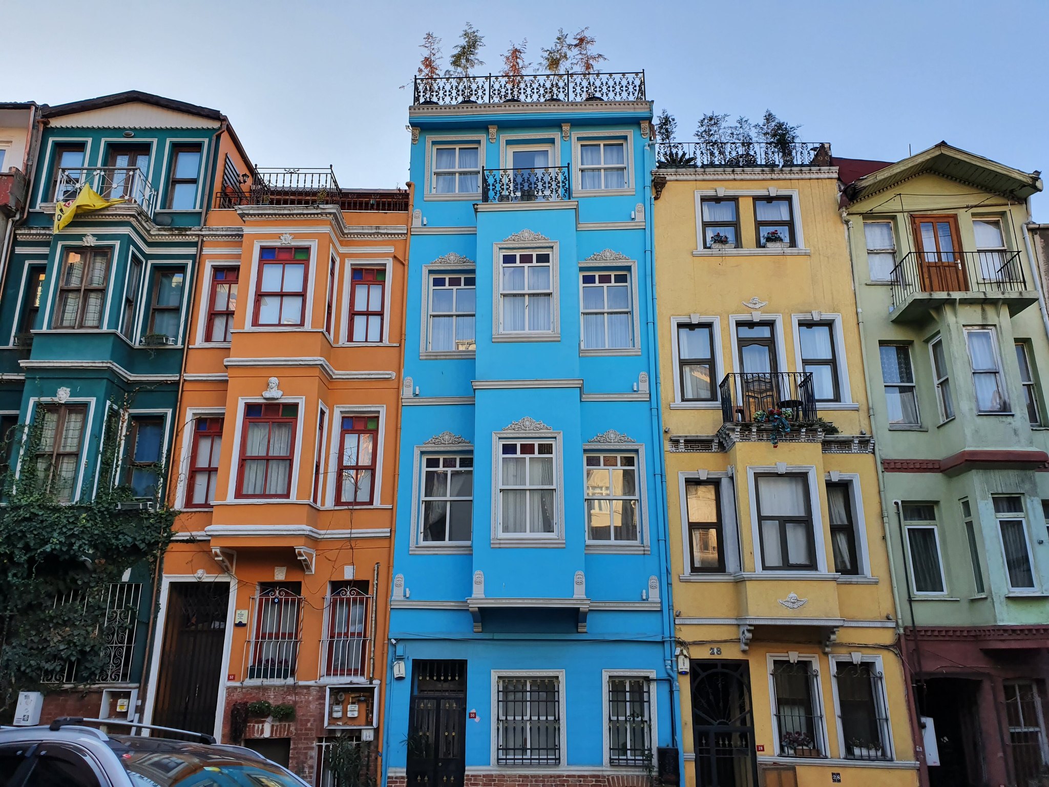 A terrace of Balat houses painted in bright blue, yellow and orange, stepping up the hill