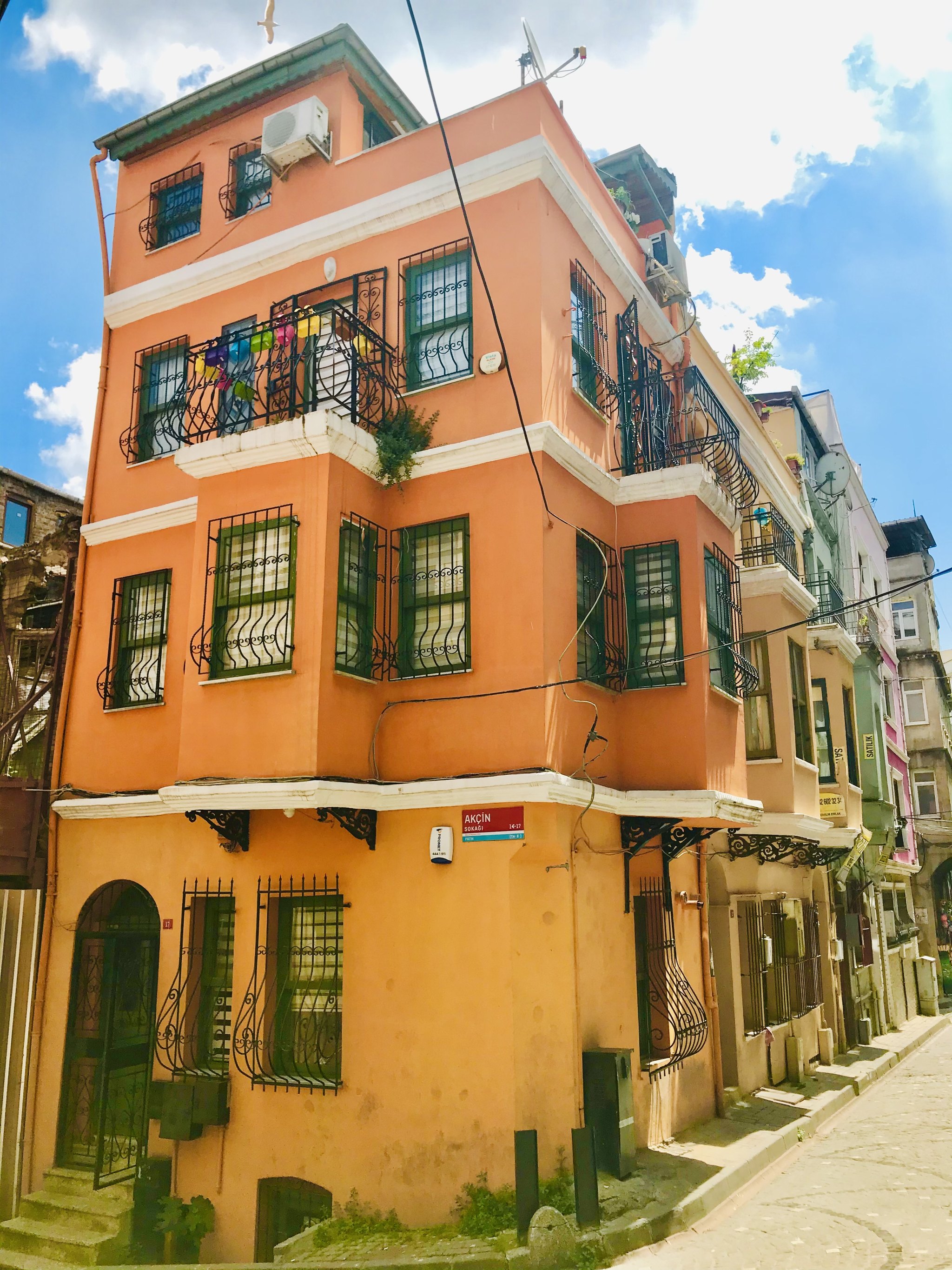 An orange corner house in Balat with bay windows, at a junction of two steep lanes