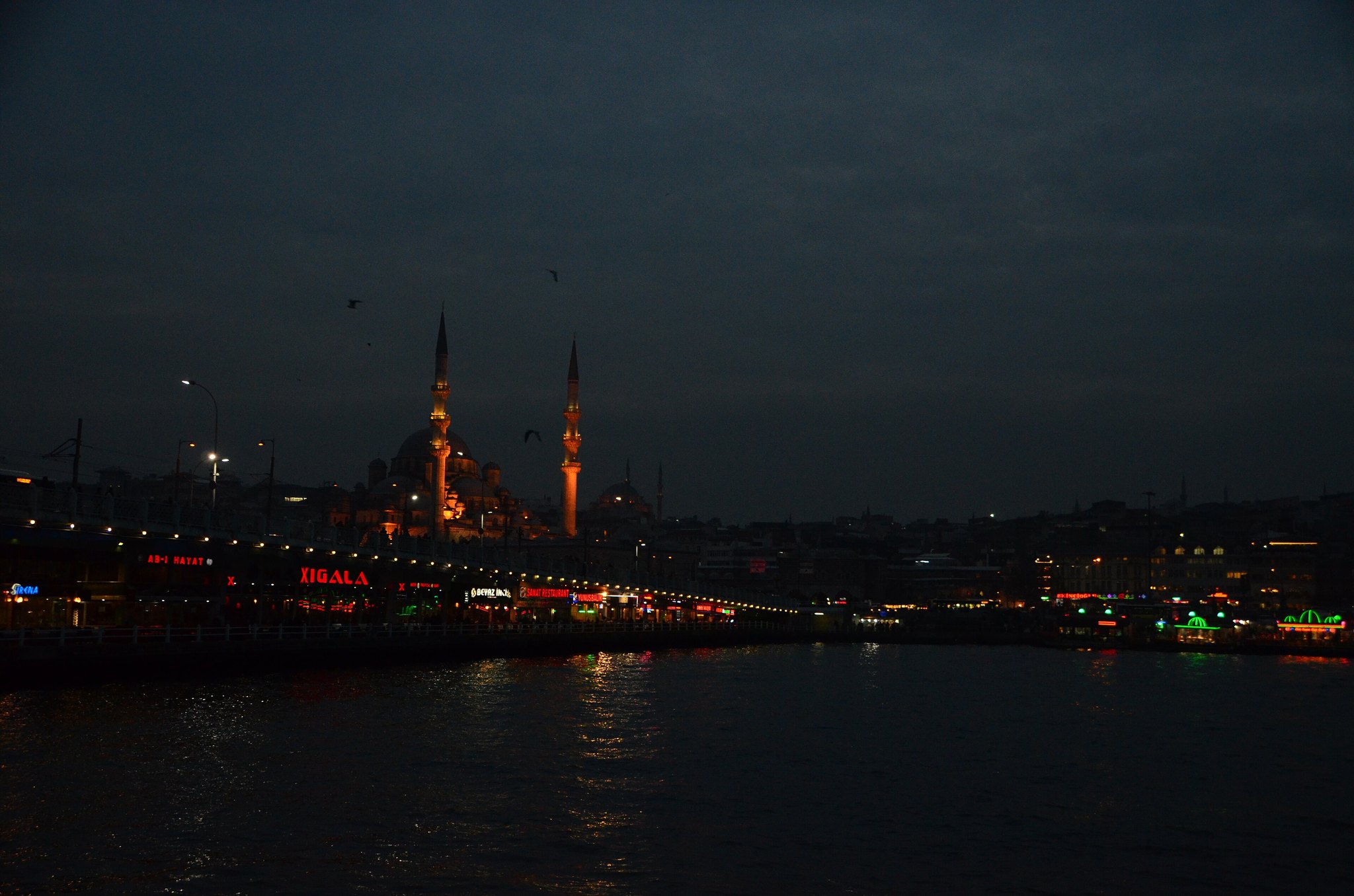 Ferries and the lit domes of the Yeni Mosque reflected in the water at night