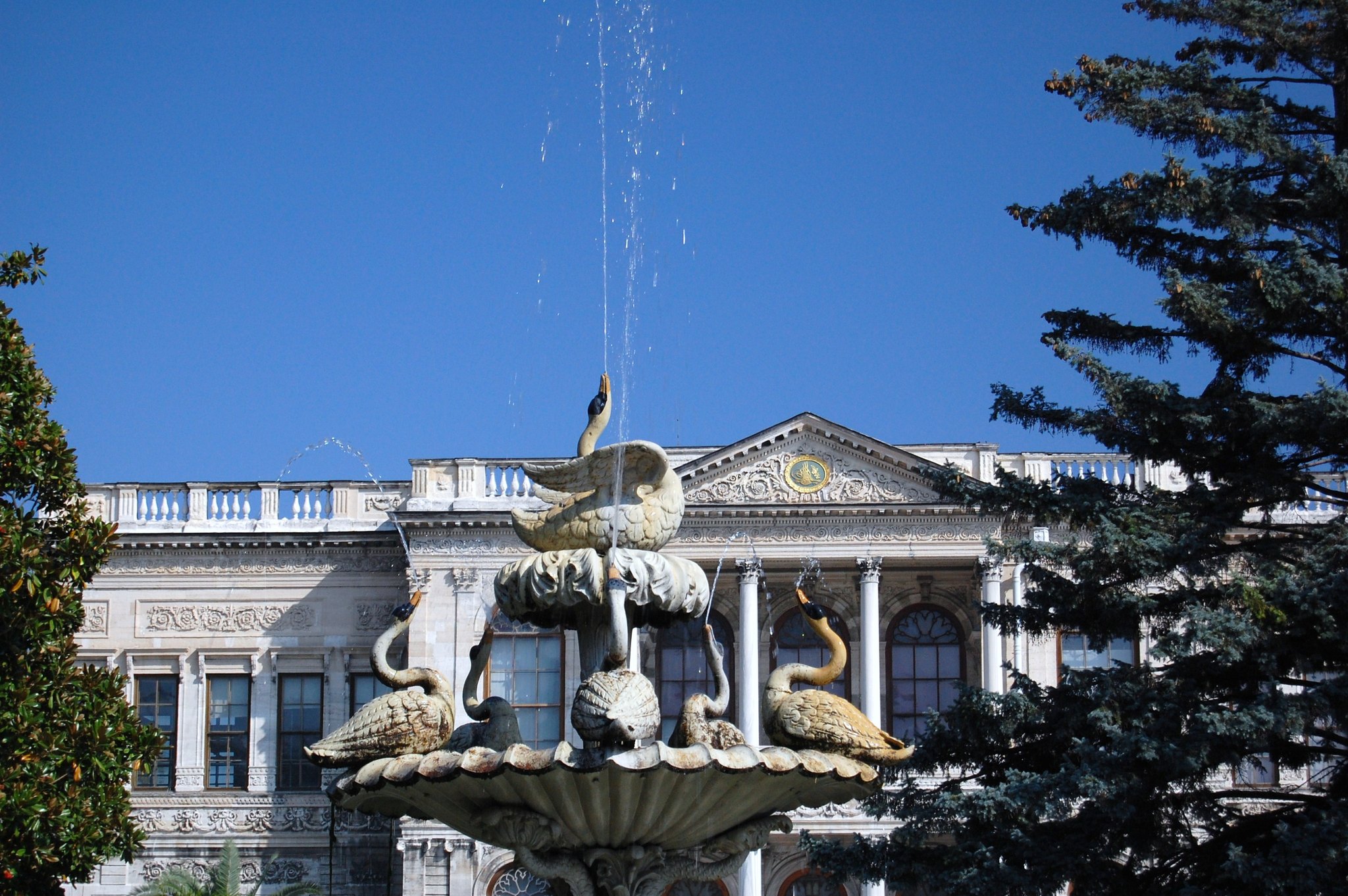The ornamental swan fountain in the garden of Dolmabahce Palace, the palace front behind it
