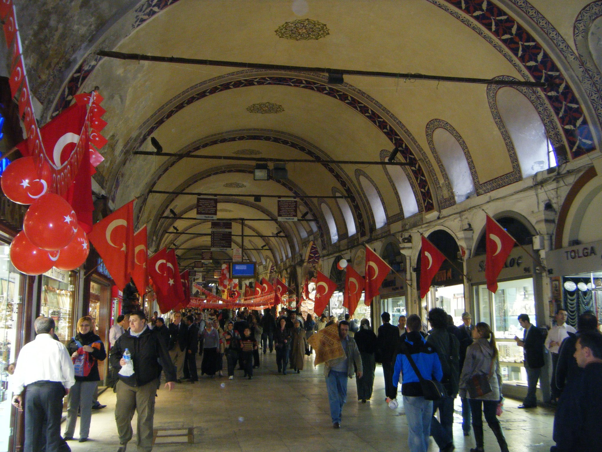 A Grand Bazaar arcade strung with red flags, shopfronts running away under the vault