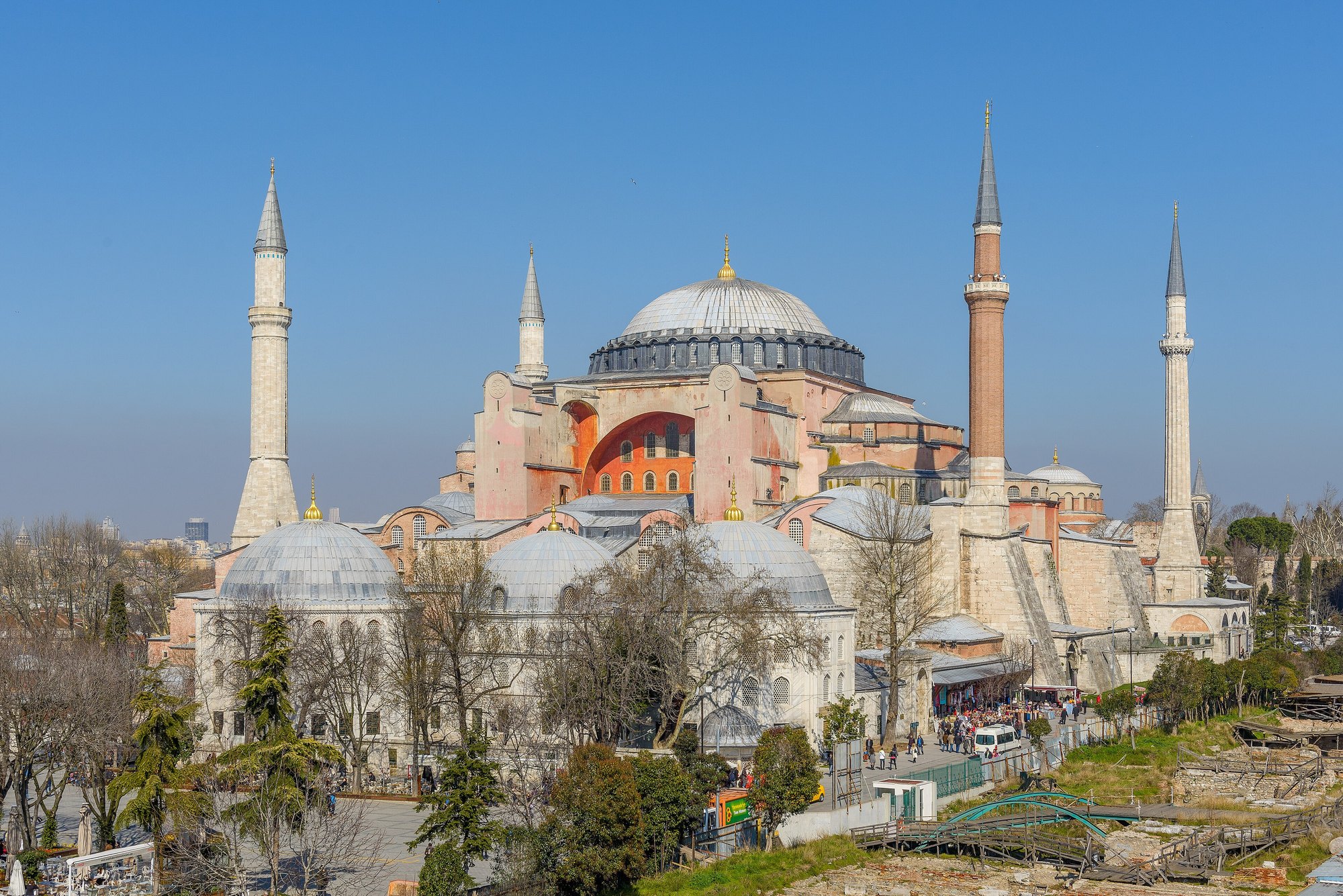 Hagia Sophia seen from the park on a clear day, its grey dome and four white minarets above the trees