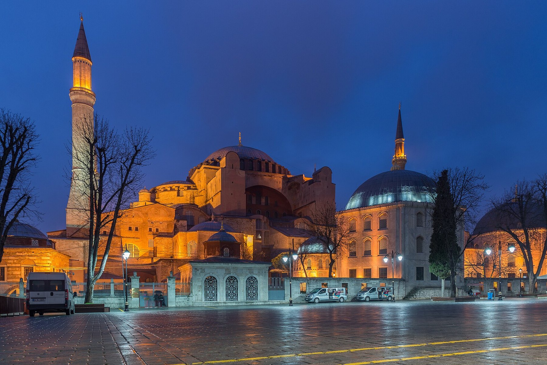 Hagia Sophia at dusk, lit warm against a deep blue sky with the square empty in front of it