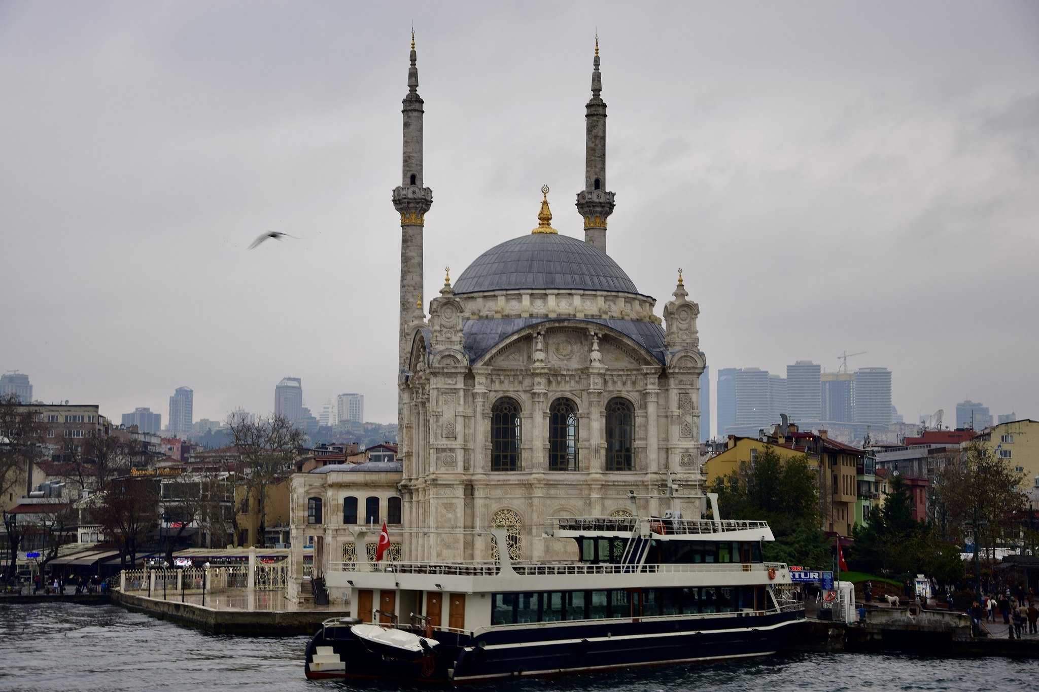 Ortakoy Mosque from the water, a ferry passing in front of its two slender minarets
