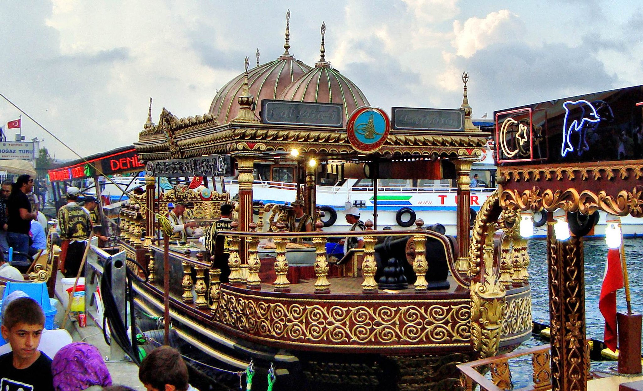 A gilded fish-sandwich boat moored at Eminonu, rocking at the quay with a queue alongside it