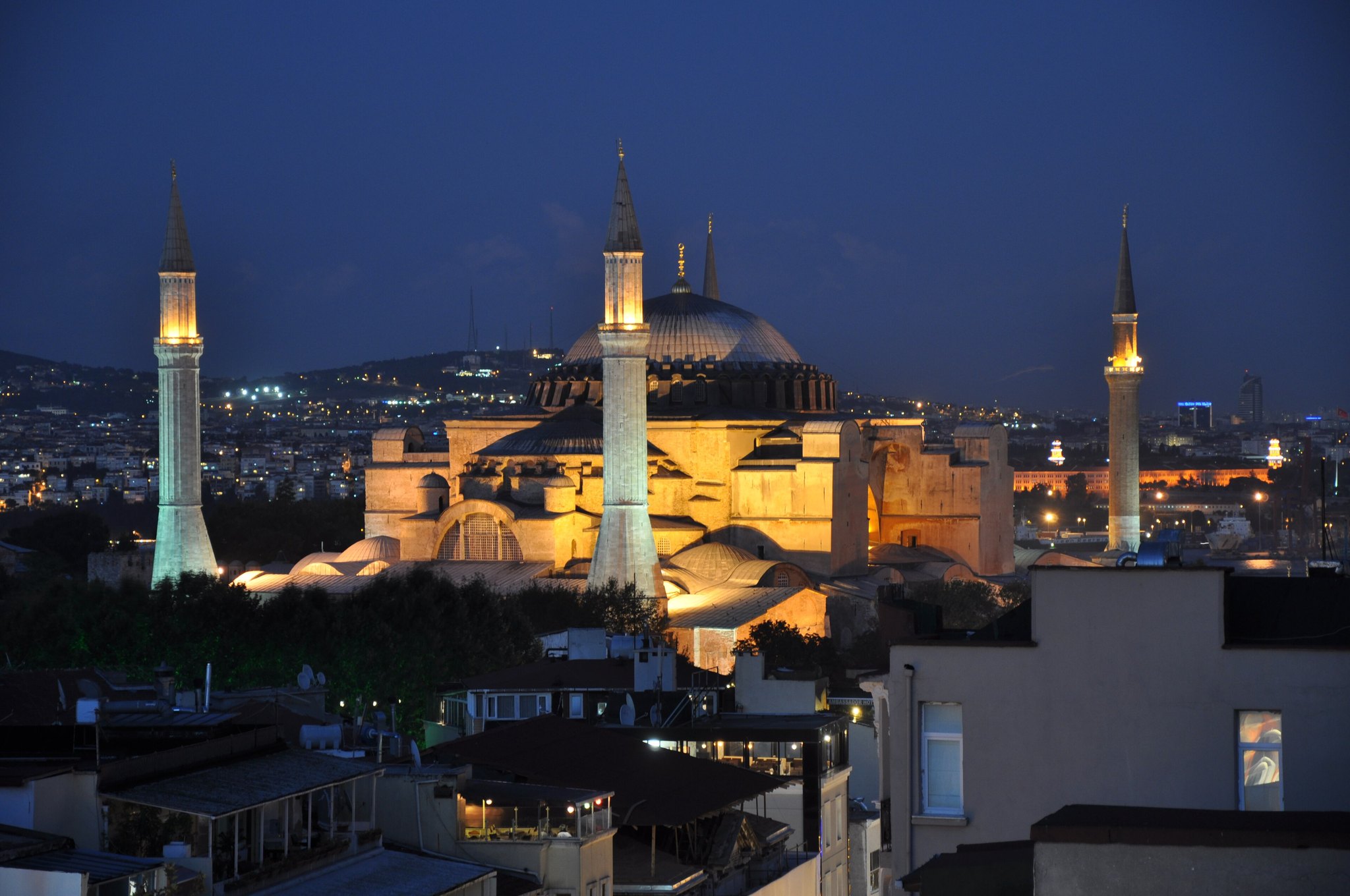 Hagia Sophia floodlit at blue hour, its walls warm gold against the deep blue sky