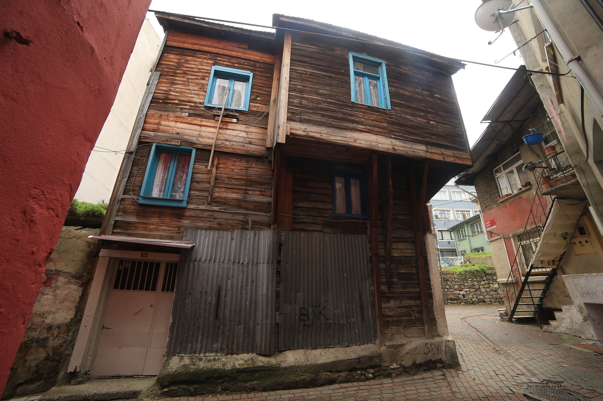 A wooden Balat house with its upper storey overhanging a narrow street of parked cars